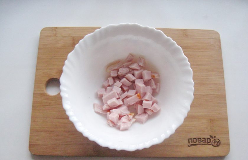 1. Этап. Салат с ананасом на Новый год: Ветчину нарежьте мелким кубиком и выложите в салатник.