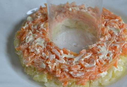 1. Этап. Гранатовый браслет салат без свеклы: И приступаем к сборке салата. В центр плоской тарелки ставим стакан или небольшую баночку, а вокруг нее выкладываем слоями сначала картофель, посолим и поперчим, смажем майонезом. Затем морковь смешаем с чесноком и выложим на картофельный слой.