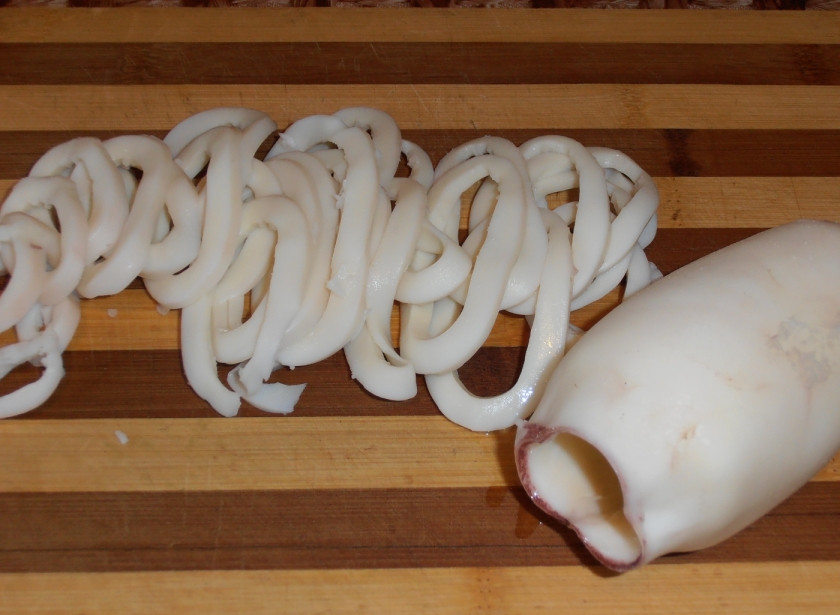 1. Этап. Салат Снегурочка: 1. Начинаем с самого главного - подготовки овощей и морепродуктов. Итак, отвариваем кальмары не более 2 минут в подсоленной воде и параллельно отвариваем овощи в мундире. Когда все ингредиенты будут готовы и остынут, приступаем к нарезанию. Кальмары следует сначала нарезать кольцами.