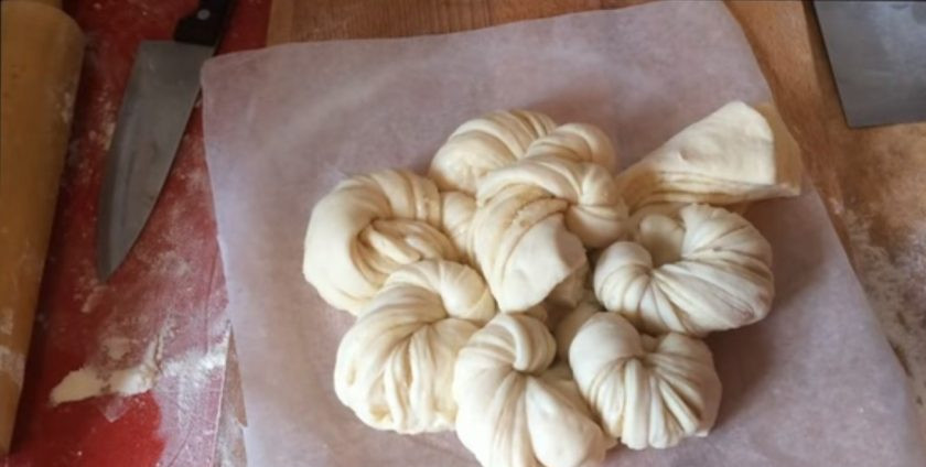 1. Этап. Булочки, политые шоколадом: Возьмите одну пару полос и перекрутите ее шесть раз, сверните жгутом и выложите по центру пирога. Вторую пару полос также перекрутите шесть раз и уложите сбоку. Остальные пары полос перекрутите и выложите по бокам пирога, чтобы получился цветок.