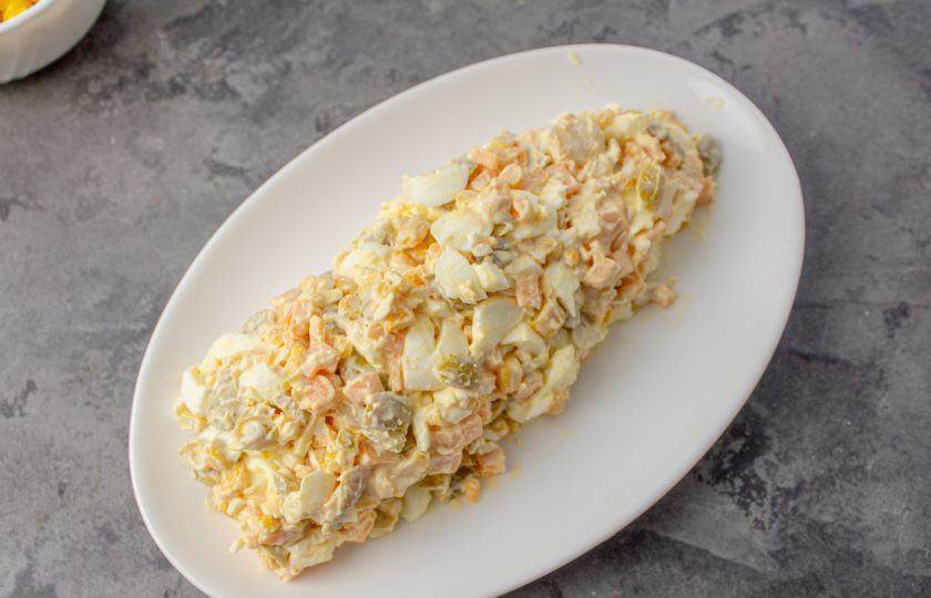 1. Этап. Салат Початок кукурузы: Выложите салат на плоское блюдо в виде овальной формы, имитируя початок кукурузы.