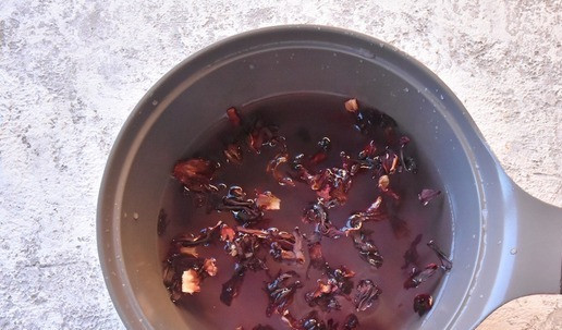 1. Этап. Рисовые биточки с киселем: Пока остывает основа для оладий готовлю кисельный соус. В воде растворяю сахар, добавляю горсть соцветий каркадэ и ставлю на огонь. Довожу до кипения, даю отвару покипеть на медленном огне пару минут.