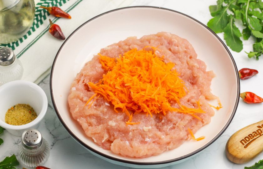 1. Этап. Куриные котлеты в аэрогриле: Выложите куриный фарш в салатник или миску. Натрите туда же на терке с мелкими ячейками морковь и репчатый лук. По желанию можно натереть очищенный зубчик чеснока.
