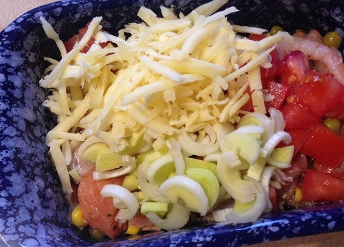 1. Этап. Рагу-чаудер из рыбы: Выкладываем в форму для запекания рыбу с креветками и овощами, добавляем лук-порей, нарезанный кубиками помидор и половину натертого сыра. Перемешаем.