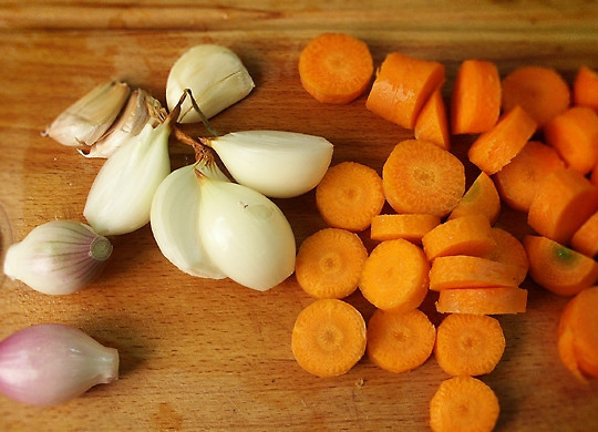 1. Этап. Гусь, тушенный с капустой: Морковь нарежьте толстыми кружочками. Лук очистите и нарежьте крупными кусками. Чеснок слегка раздавите с помощью ножа.