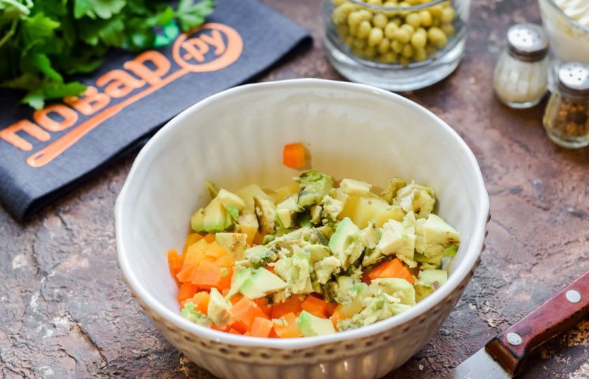 1. Этап. Оливье с курицей и авокадо: Авокадо очистите и нарежьте небольшими кубиками, добавьте авокадо в салат.