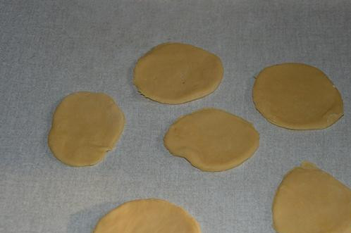 1. Этап. Печенье Конвертики с творогом: Тем временем подготовьте начинку. Для этого тщательно разотрите творог с остальным сахаром и смешайте со сметаной. Тесто раскатайте и вырежьте кружки.