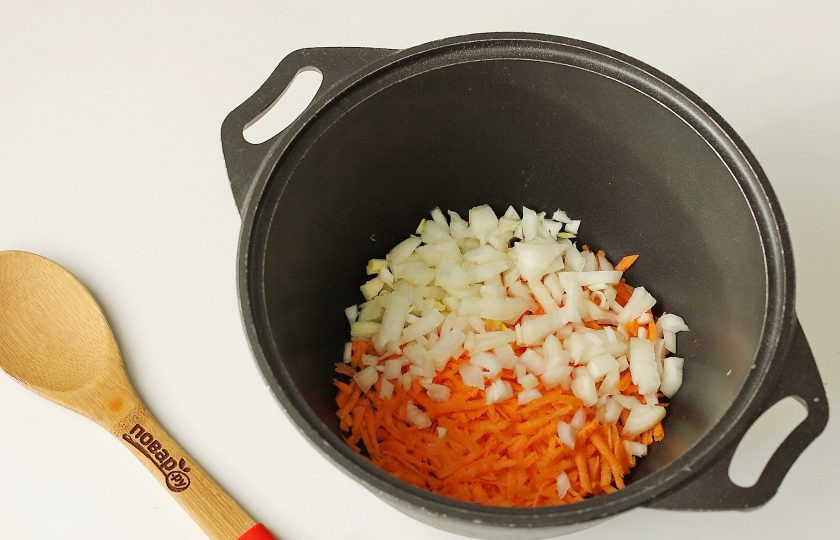 1. Этап. Пельмени в казане: В казан налейте масло, накалите его и выложите тертую морковь и нарезанный кубиками лук.