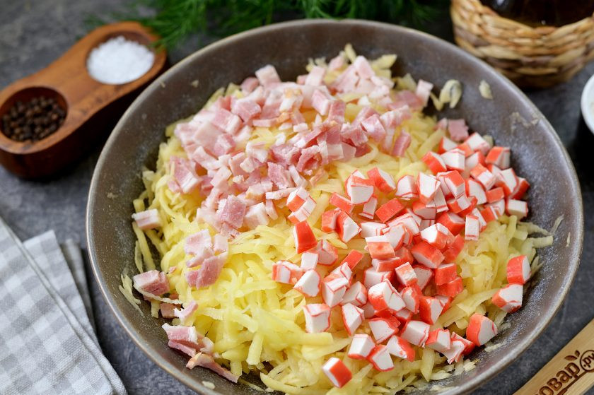 1. Этап. Драники с беконом и крабовыми палочками: Крабовые палочки почистите от упаковки, нарежьте их мелко вместе с беконом, переложите в миску к картофелю.