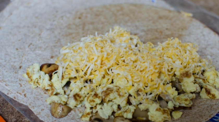 1. Этап. Кесадилья с грибами: Заполняем тортильи. Кладем измельченный омлет, грибы, терты сыр. Сворачиваем пополам и кладем на сковородку в масло. Обжариваем кесадилью на небольшом огне с двух сторон до золотистой корочки. Делать это надо довольно быстро и ловко, лепешка может легко и быстро сгореть.