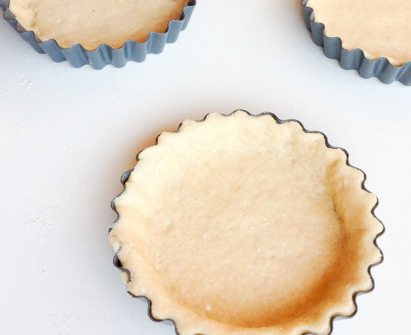 1. Этап. Корзиночки из творожного теста с ягодами: Вырежьте с помощью стакана круги из теста, распределите их по формочкам для корзинок, придавливая тесто и формируя бортики. Обрежьте лишнее тесто по краям. Оставьте немного для дальнейшего украшения корзиночек.