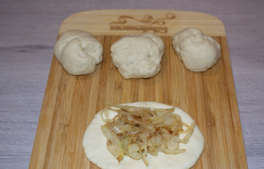 1. Этап. Пирожки с капустой духовые: Тесто разделите на небольшие шарики. Один шарик теста раскатайте в блинчик. Выложите в центр него начинку.