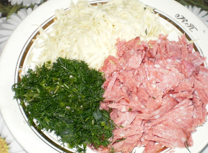 1. Этап. Пирожки с колбасой и сыром: Первым делом размораживаем тесто и приступаем к начинке. Трем сыр на крупной терке, колбасу и зелень мелко нарезаем, кстати, колбаса здесь подойдет любая. Перемешиваем все ингредиенты, при необходимости солим и перчим.