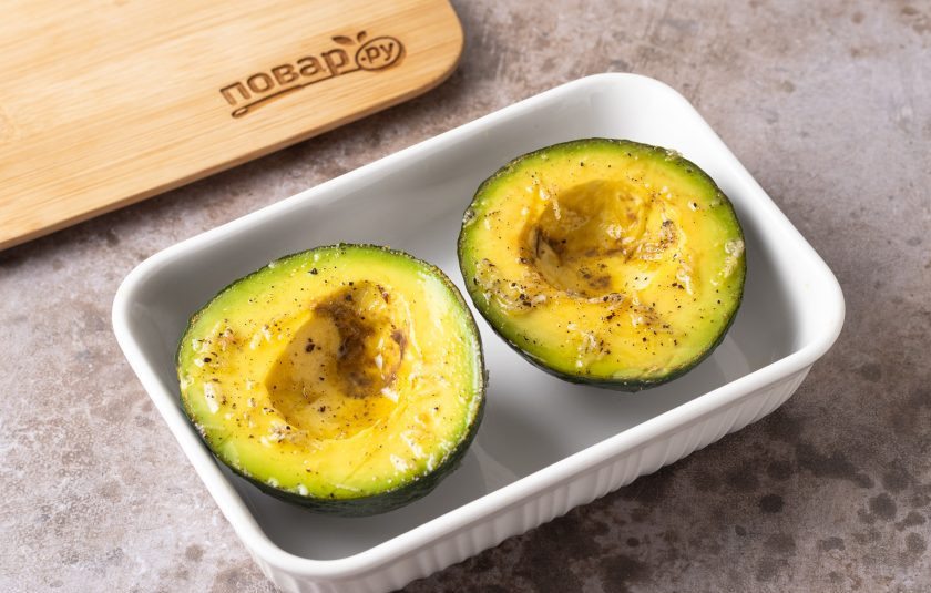 1. Этап. Запеченный авокадо: Авокадо разрежьте пополам. Удалите косточку. Смажьте растительным маслом с натертым зубчиком чеснока. Посолите и поперчите. Запекайте в разогретой до 200 градусов духовке 15 минут.