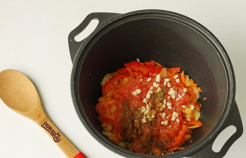 1. Этап. Пельмени в казане: Обжарьте все вместе в течение двух минут и добавьте тертую на терке мякоть помидора (шкурку я выбрасываю). Добавьте нарезанный мелкими кубиками чеснок и любимые специи по вкусу.