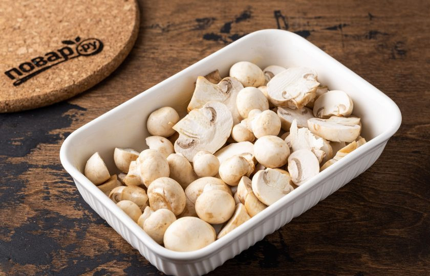 1. Этап. Шампиньоны с кедровыми орешками: Шампиньоны промойте, обсушите. Крупные грибы разрежьте на ломтики средней толщины, а маленькие можно оставить целыми. Выложите их в форму для запекания смазанную растительным маслом.