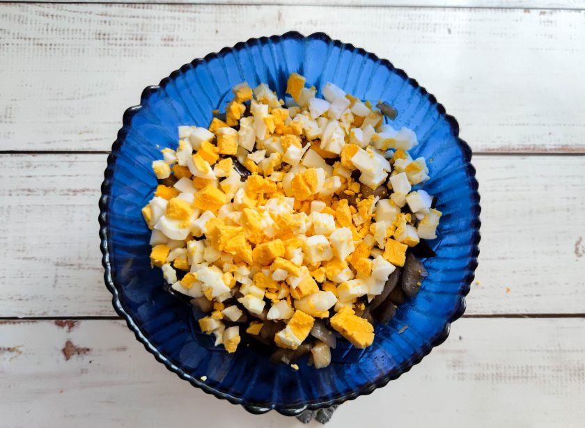 1. Этап. Салат из жареных баклажанов с майонезом: Вареные яйца очистите от скорлупы, мелко нарежьте и добавьте к баклажанам.