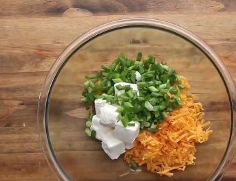 1. Этап. Запеченные картофельные вулканчики: Пока готовится картофель, приготовим начинку. Смешаем мелко нарезанный лук, 300 г Чеддера, натертого на средней терке, и сливочный сыр.