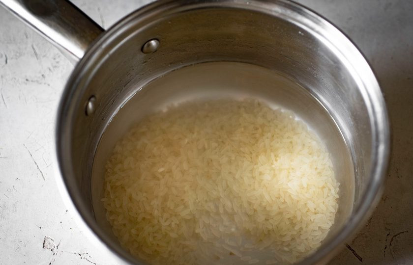 1. Этап. Фаршированные перцы в аэрогриле: Промытый рис выложите в сотейник, залейте водой и отворите почти до готовности, затем слейте воду, откинув на дуршлаг.