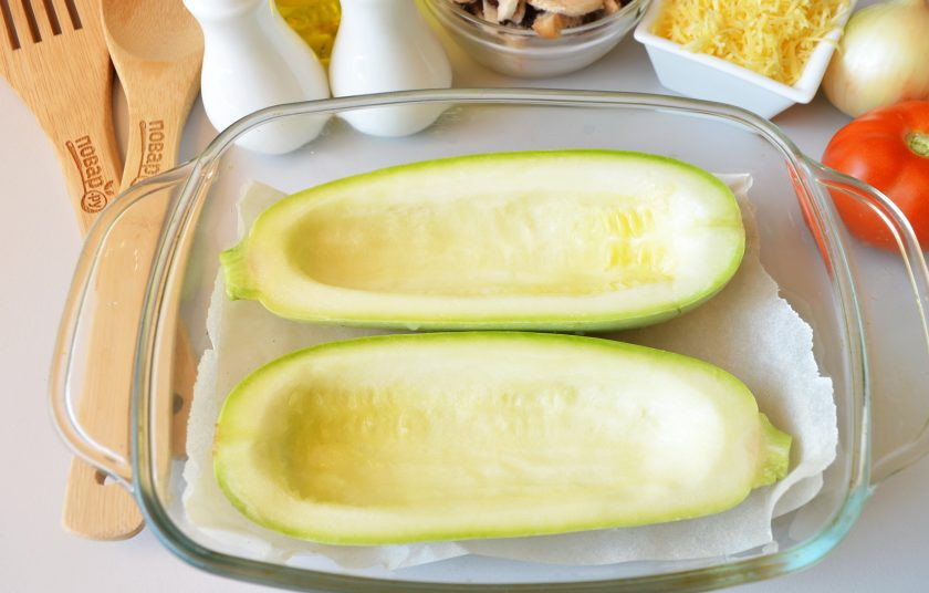 1. Этап. Лодочки из кабачков с грибами в духовке: Кабачок разрежьте на две равные половинки. С помощью острого ножа и кофейной ложки удалите мякоть, чтобы получились красивые лодочки. Толщина стенок должна быть не менее 7-8 мм, чтобы лодочка держала форму. Посолите заготовки, положите их в противень для запекания.