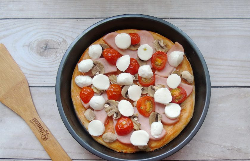 1. Этап. Пицца с ветчиной и грибами: Когда пицца будет готова, достаньте её из духовки и покройте нарезанной моцареллой.