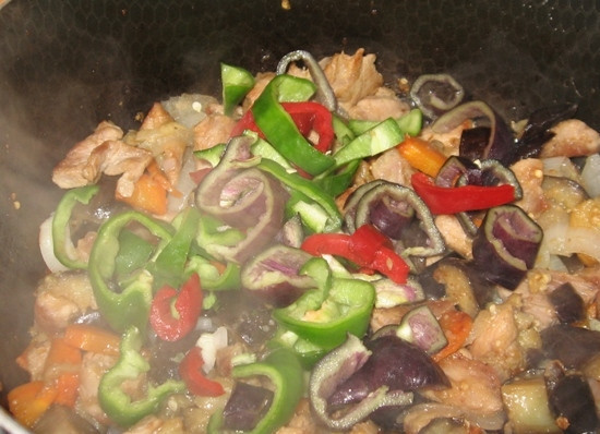 1. Этап. Баклажаны, жаренные со свининой: Через 5 минут после моркови, отправляем в сковородку подготовленный лук. Перемешиваем — и еще через 5 минут туда же отправляем перец.