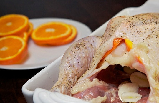 1. Этап. Запеченная курочка в духовке: 5. Выложите чеснок внутрь курицы. Часть чеснока, как и оставшиеся апельсины, можно выложить в форму рядом с птицей.