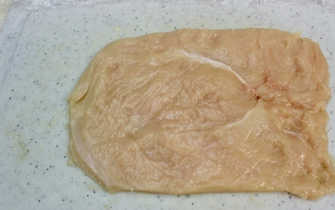 1. Этап. Сочные куриные грудки: 2. Выложите мясо на лист пищевой пленки и накройте вторым листом пленки. Аккуратно отбейте молоточком, чтобы получился ровный пласт.