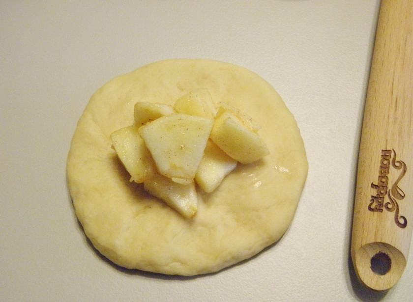 1. Этап. Расстегаи с яблоками: Разделите тесто на 14 частей. Каждую часть раскатайте, как на вареник. В центр положите начинку.