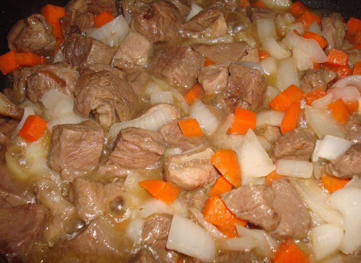 1. Этап. Баранина в горшочке в духовке: Теперь наливаем на сковородку растительное масло и обжариваем на сильном огне баранину со всех сторон до золотистого цвета. Потом добавляем к мясу нарезанную морковь и репчатый лук, жарим все еще пару минут, затем перекладываем баранину с овощами на дно горшочка, посыпаем все солью и молотым перцем.