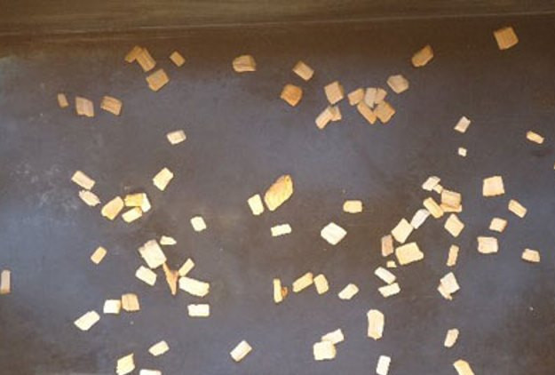 1. Этап. Ребрышки копченые: Пока ребрышки маринуются, подготовьте коптильню. Уложите на дно небольшое количество ольховой щепы. Установите поддон для сбора жира.