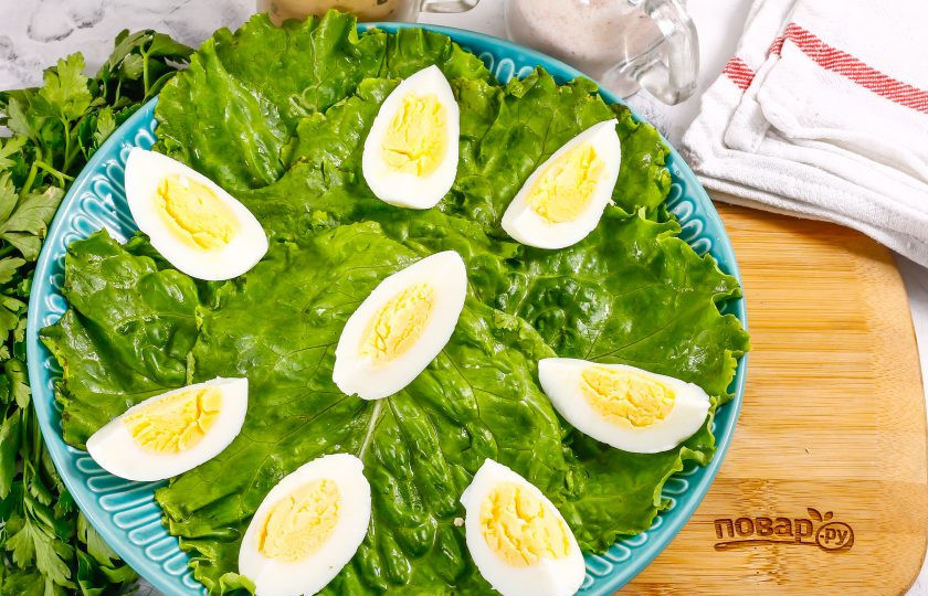 1. Этап. Салат с тунцом и вялеными помидорами: Куриные яйца очистите от скорлупы, промойте в воде и нарежьте четвертинками. Выложите их на листья салата.