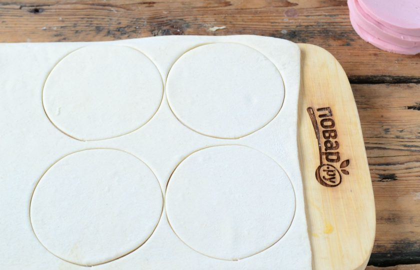 1. Этап. Слойки с колбасой Зигзаг: Тесто тонко раскатайте тесто. Подберите круглую форму диаметром равную диаметру колбасы. Я использую металлическую форму, но можно подобрать подходящее блюдечко, чашку и т.д. Выдавите кружочки из теста, их должно получиться ровно в 2 раза больше, чем кружочков колбасы.