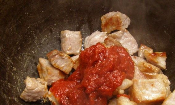 1. Этап. Мясо, тушенное в сметане: Переложите обжаренное мясо в кастрюльку с толстым дном или в казанок. Добавьте к мясу томатную пасту.