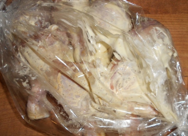 1. Этап. Куриные ножки с рисом в рукаве: 4. Сливаем воду с риса, достаем голени с холодильника. Открываем рукав для запекания, кладем внутрь рис, разравниваем его. На него выкладываем ножки и выливаем остатки маринада. Добавляем 2 столовые ложки воды.