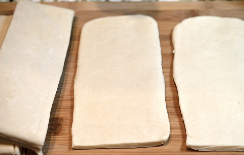 1. Этап. Простое слоёное пирожное: В упаковке слоеного теста 2 квадратных листа, каждый из которых раскатайте в одном направлении до получения прямоугольной формы. Каждый прямоугольник разрежьте на 4 части, получив таким образом 8 листочков теста.