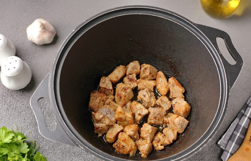 1. Этап. Картошка тушёная со свининой и фасолью: В казане или любой посуде с толстым дном разогрейте масло, выложите мясо и на сильном огне обжарьте до лёгкой румяной корочки.