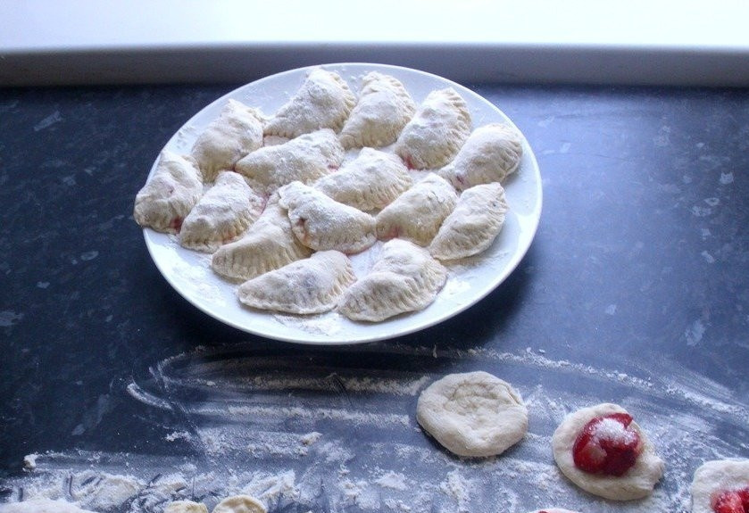 1. Этап. Вареники с клубникой на кефире: 3. Нарезаем клубнику, добавляем сахар (по вкусу), после чего выкладываем клубнику в центр кружочка и формируем классические вареники. Главное — плотно защипнуть края каждой лепешки с начинкой. Пока лепятся вареники, можно закипятить и подсолить воду, а уже после отправлять в неё наши вареники.