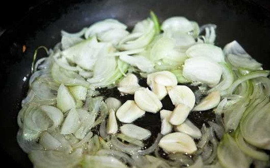 1. Этап. Тефтели в томате: 6. А тем временем можно заняться соусом. На сковороду отправьте немного масла, разогрейте его. Очистите и измельчите лук с чесноком. Выложите их на сковороду и обжарьте пару минут.