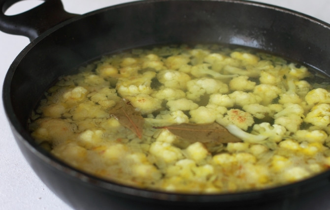 1. Этап. Белый борщ: Вливаем в сковороду воду до уровня (5-6 см цветной капусты). Кладем лавровый лист и доводим до кипения. Тушим на среднем огне, примерно 10 минут, до мягкости капусты.