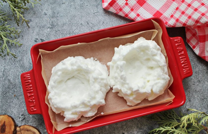 1. Этап. Яйца в пуховом гнезде: К белкам выложите щепотку соли и взбейте в плотную пену. Форму для запекания застелите пергаментом для запекания и разделив белки на две части, сформируйте круги с углублением посередине.