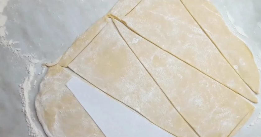 1. Этап. Вкусный пирог с капустой и мясом: 1. Тесто на кефире раскатайте в пласт толщиной примерно 3 мм. С помощью ножа (у меня это нож для пиццы) и лекала вырежьте треугольники, которые послужат лепестками пирога. На форму диаметром 28 см необходимо 9 таких лепестков.