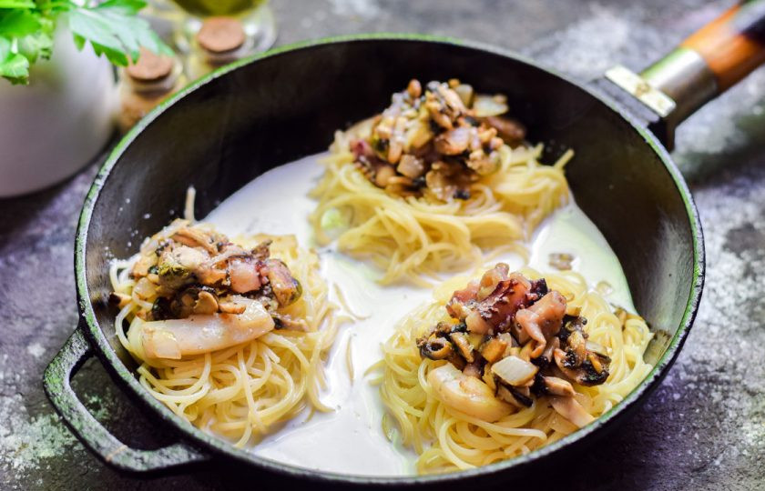 1. Этап. Гнезда с морепродуктами: Залейте в сковороду сливки и добавьте специи. Готовьте блюдо под крышкой 6-8 минут.