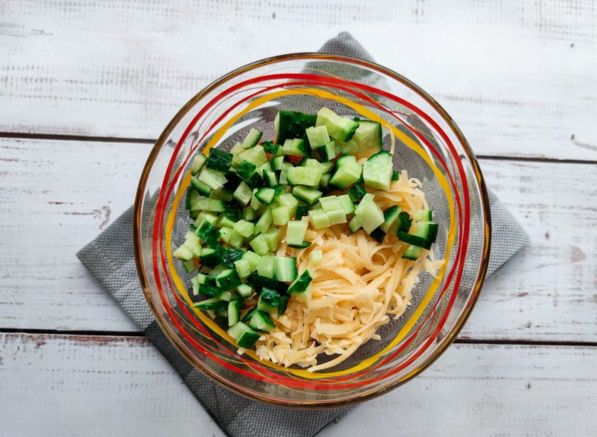 1. Этап. Салат Калейдоскоп с крабовыми палочками: Огурец хорошо помойте, обсушите бумажным полотенцем, нарежьте небольшими кубиками и выложите в тарелку.