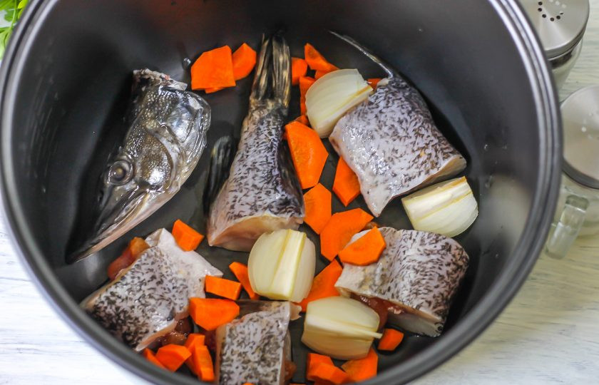 1. Этап. Уха из щуки в мультиварке: Щуку нарежьте крупными кусочками и выложите в чашу мультиварки. Очистите от кожуры лук и морковь, промойте в воде и разрежьте лук на четыре части, а морковь нарежьте крупными кусочками. Добавьте овощные нарезки в чашу к рыбе.