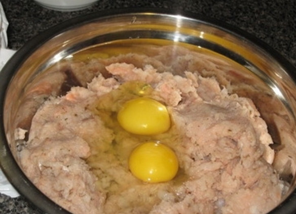 1. Этап. Рыбный рулет с яйцом: Промойте рыбное филе под проточной водой, удалите кожу и косточки. Уложите в блендер и измельчите. Выложите фарш в миску, посолите, поперчите и добавьте два яйца.