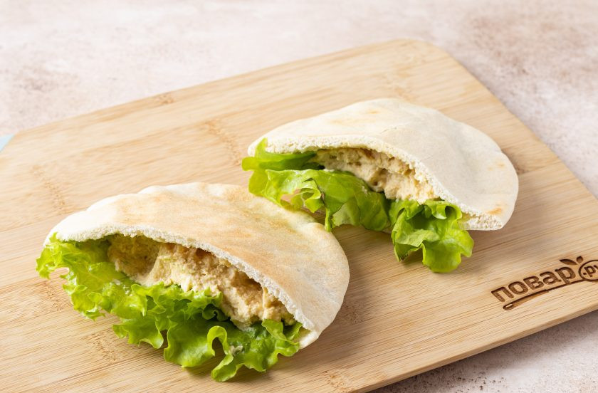 1. Этап. Пита начиненная хумусом и весенним салатом: Разрежьте питу пополам. Вложите в каждую половинку лист салата. Добавьте 1-2 ст.л. хумуса.