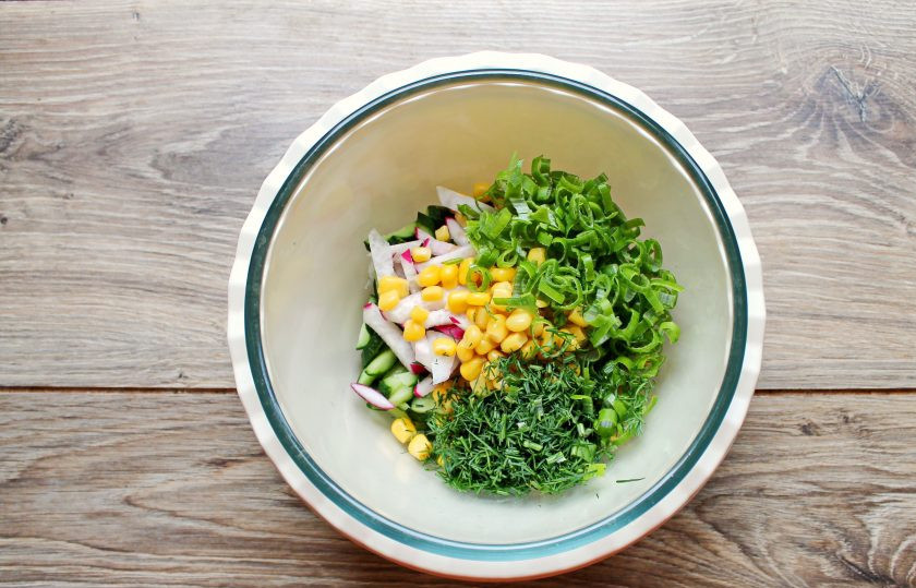 1. Этап. Постный салат с кукурузой: Зеленый лук и укроп порежьте и добавьте в салатник.