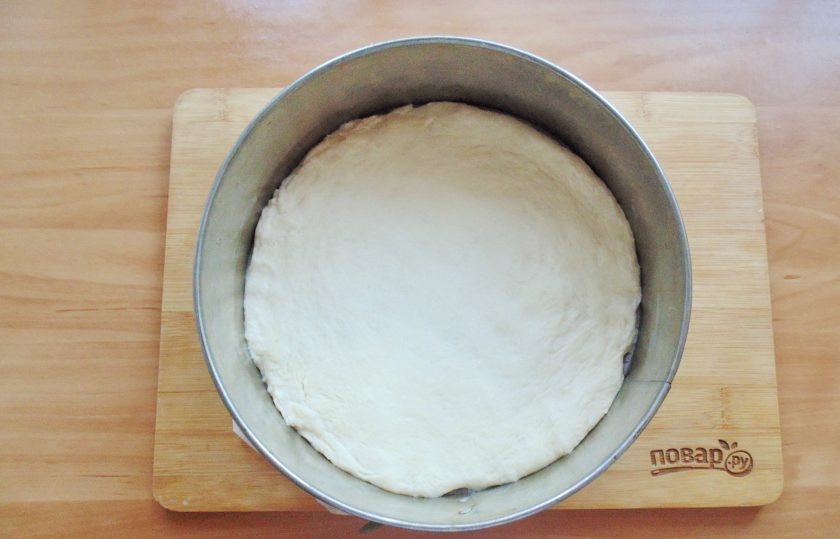 1. Этап. Испанская пицца: Тесто разделите на две части. Раскатайте одну часть в круг толщиной 6-7 миллиметров. Выложите в форму для запекания. Смажьте слегка растительным маслом.