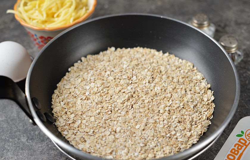 1. Этап. Жареная овсянка с яйцом: Выложите хлопья в сковороду с антипригарным покрытием, обжаривайте овсянку несколько минут до легкого орехового аромата.